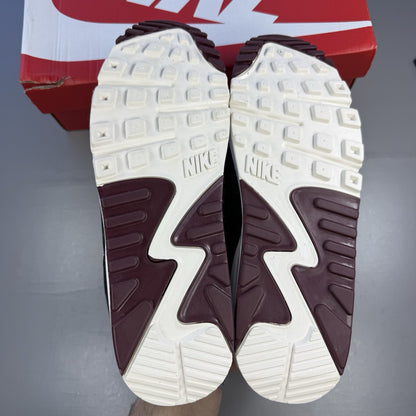 Nike Air Max 90 grey trainers with burgundy accents and black detailing.