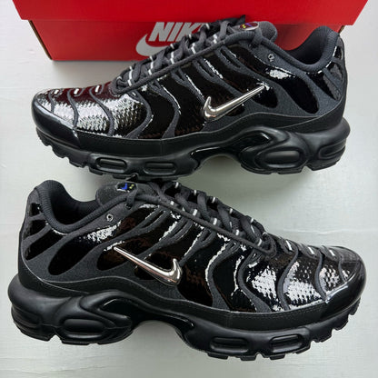 Nike black Air Max Plus TN trainers with chrome accents and vibrant volt detailing.