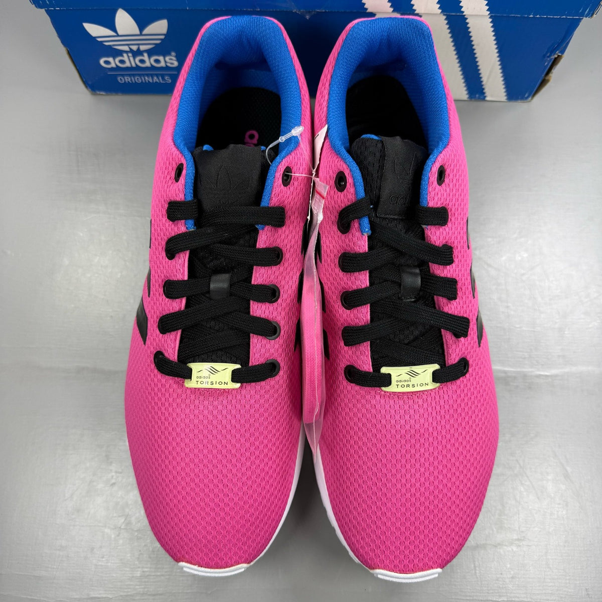 Adidas ZX Flux trainers in shock pink with black and blue accents, mesh upper.