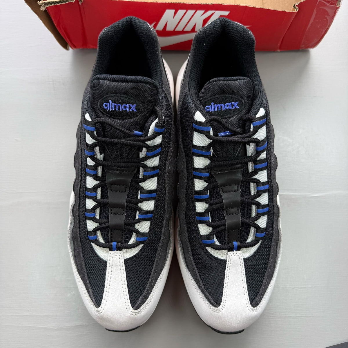 Nike black trainers with grey and white accents, featuring Air Max cushioning and logo.