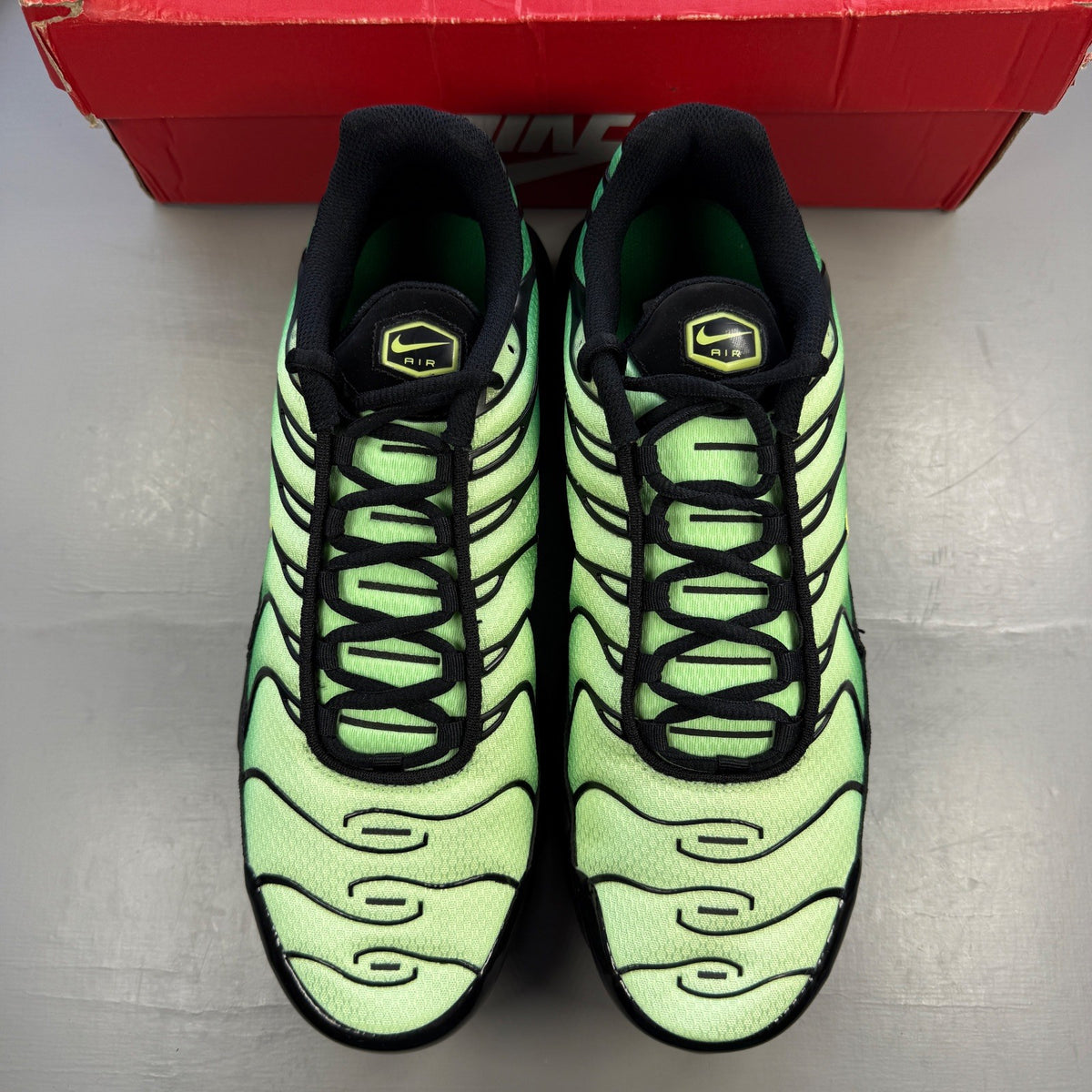 Nike Air Max Plus TN green trainers with logo detailing and mesh material.