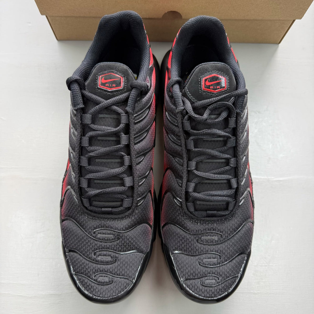 Nike Air Max Plus TN black trainers with crimson and noble red accents, mesh upper.