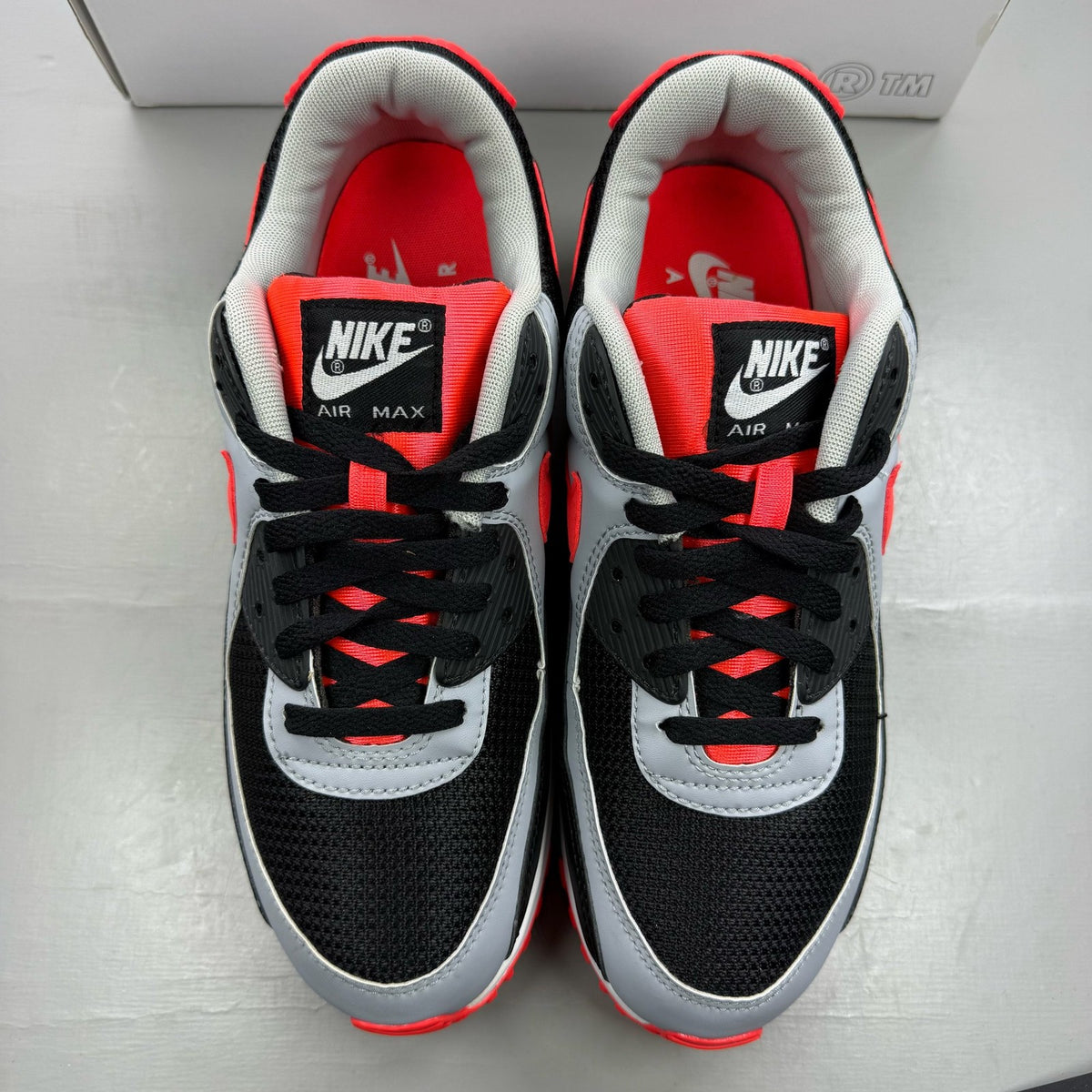 Nike Air Max 90 black trainers with radiant red and wolf grey accents, logo detail.
