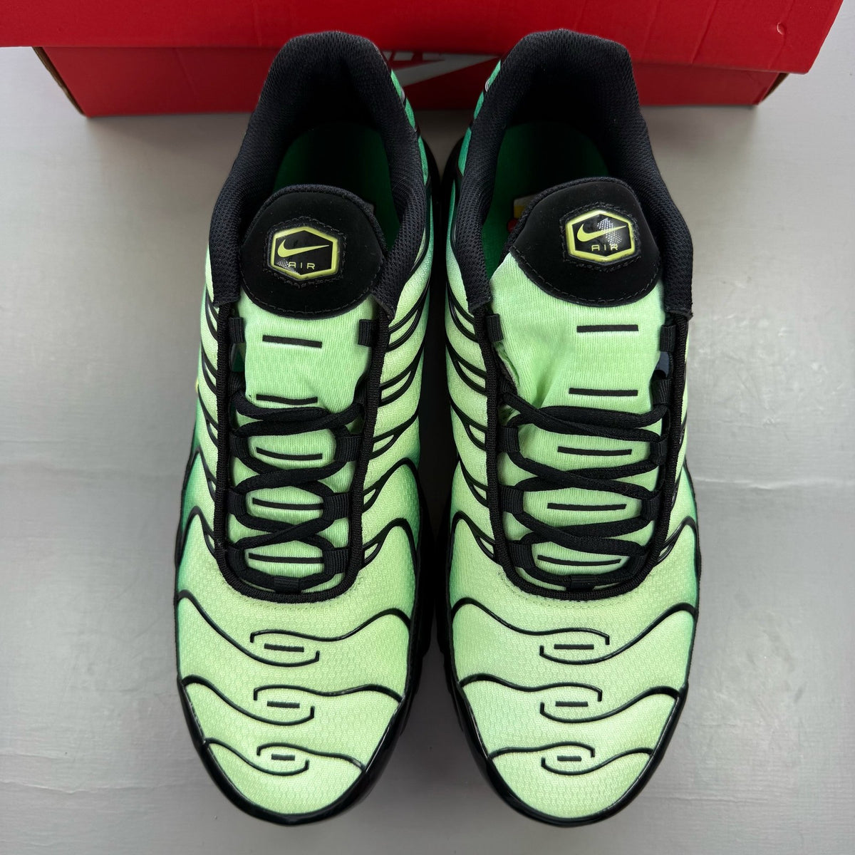 Nike Air Max Plus TN green trainers with lemon twist accents and distinctive logo.