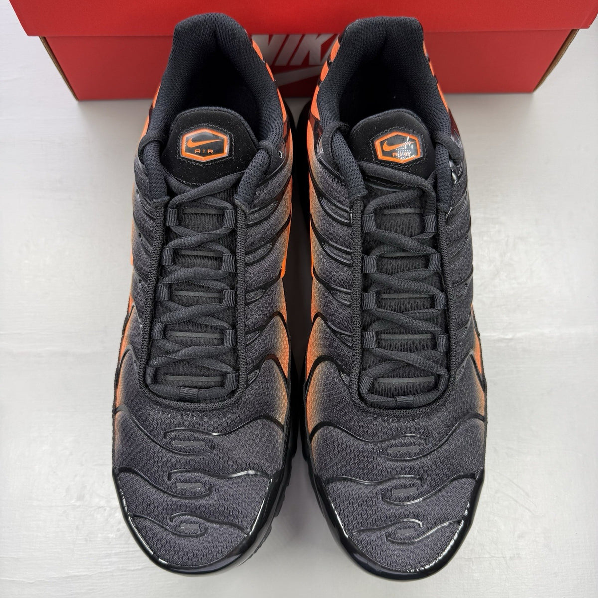 Nike Air Max Plus TN black trainers with total orange accents and signature logo.