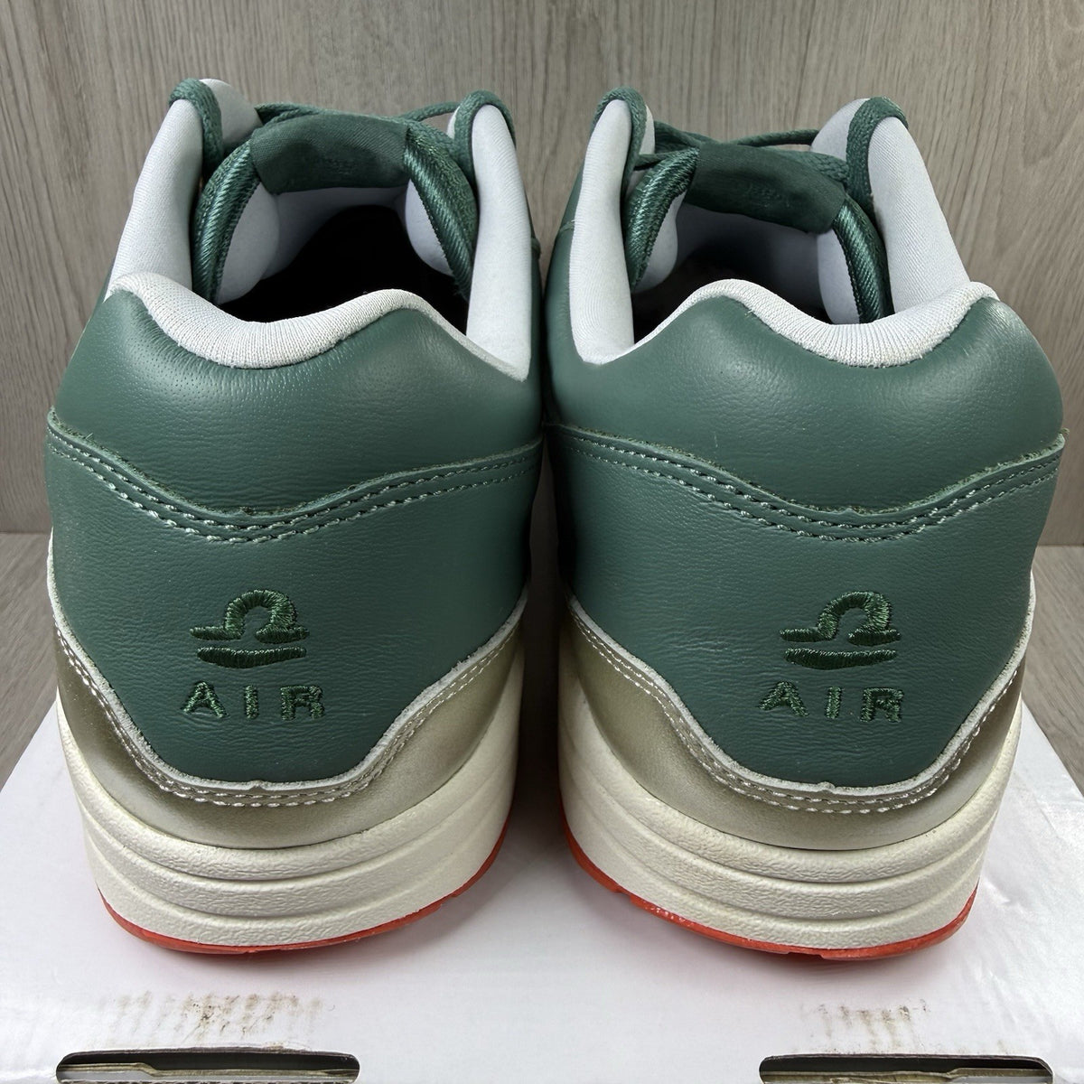 Nike Air Max 1 trainers green with white and silver accents, featuring iconic logo.