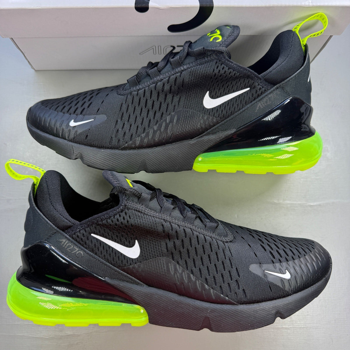 Nike Air Max 270 black trainers with neon volt green accents and white sole.