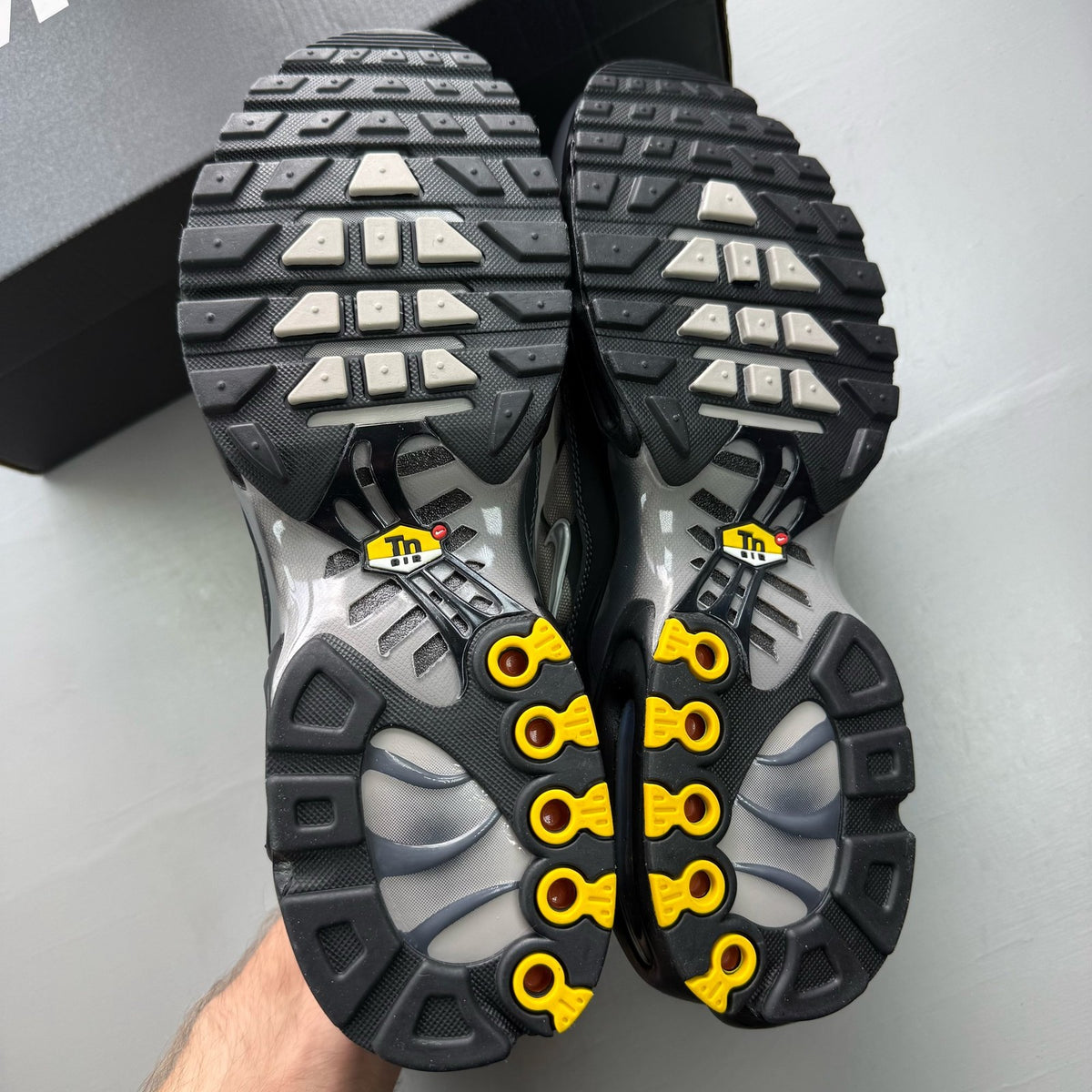 Nike black trainers with dark smoke grey accents and signature Air Max Plus design.