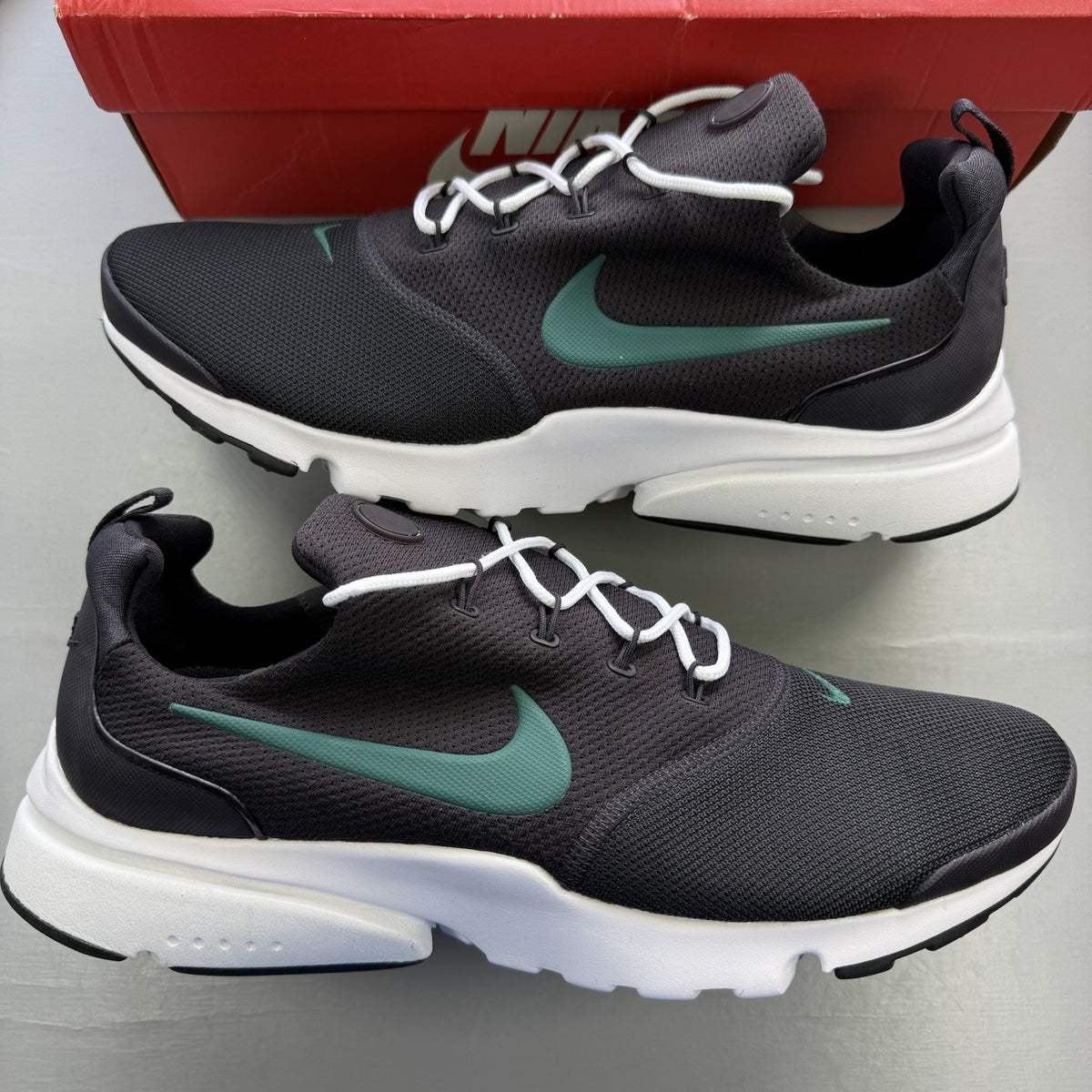 Nike Presto Fly black trainers with grey accents and white sole, featuring logo details.
