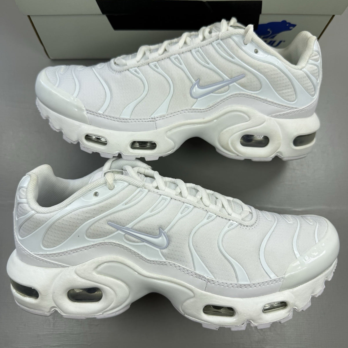 Nike Air Max Plus TN white trainers with metallic silver accents and grey detailing.