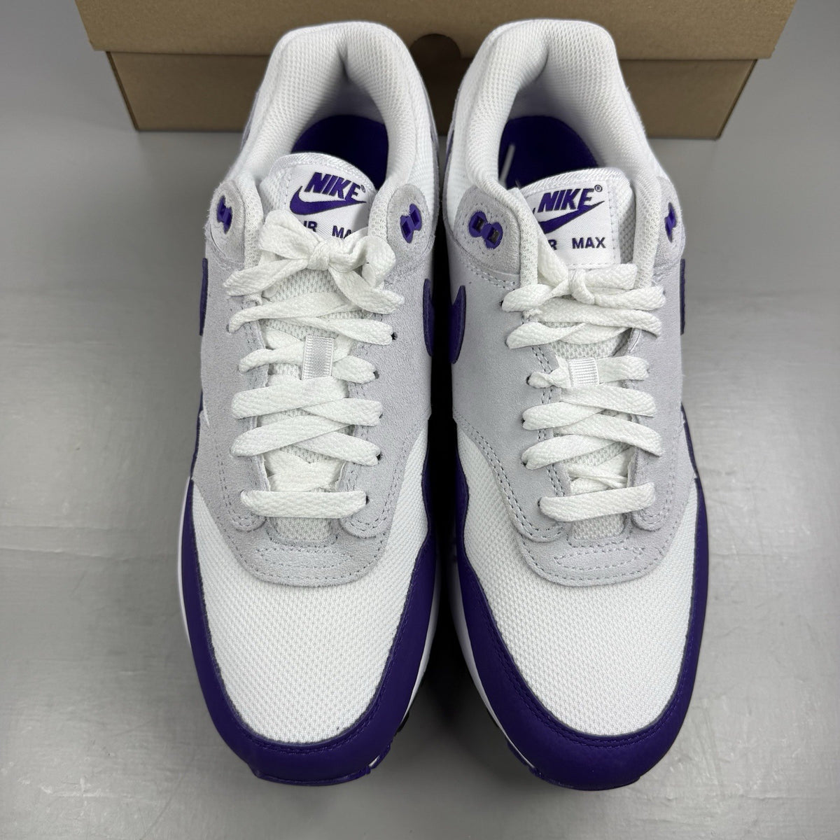 Nike Air Max 1 SC white trainers with purple and black accents, featuring logo detail.